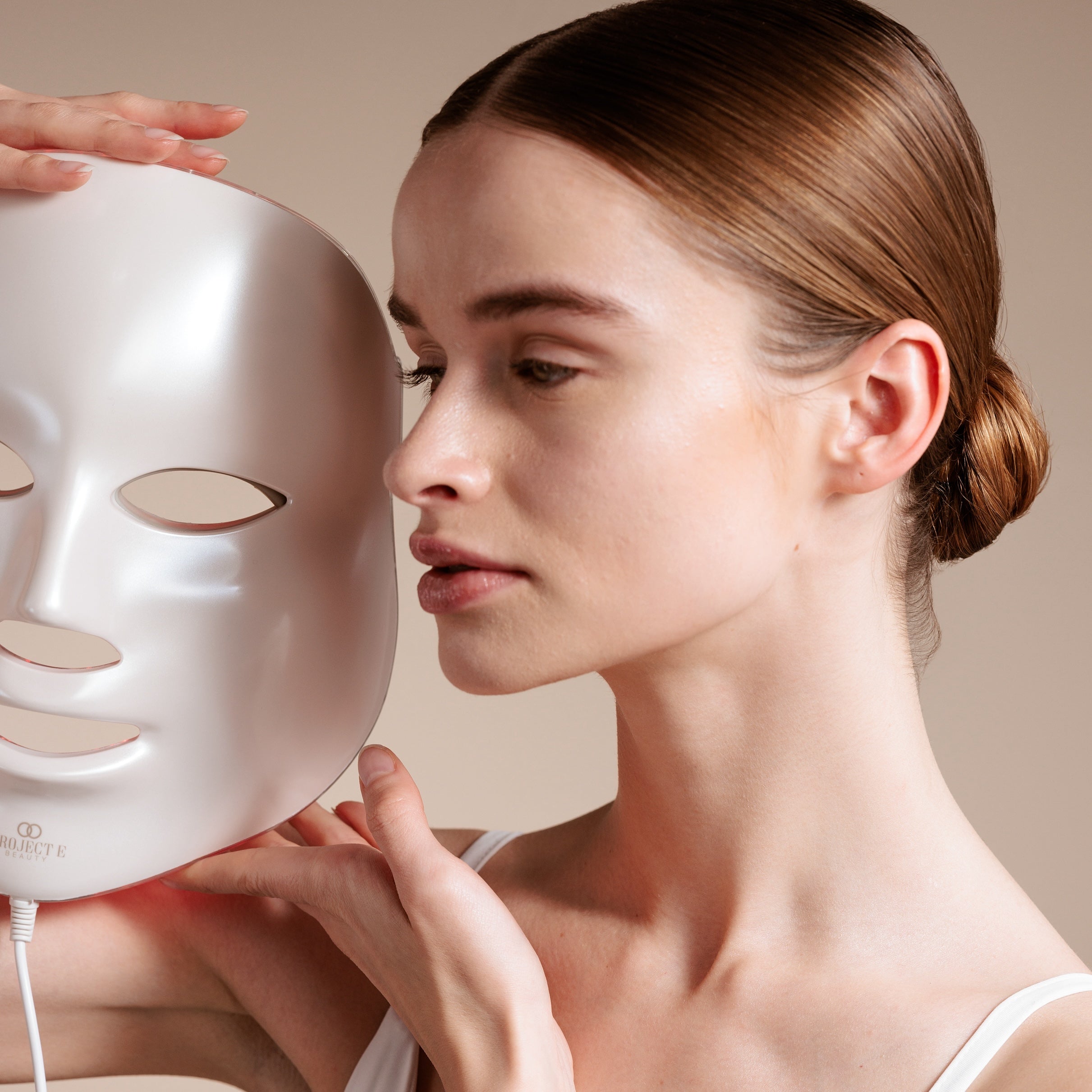 Girl holding red light therapy mask near her face